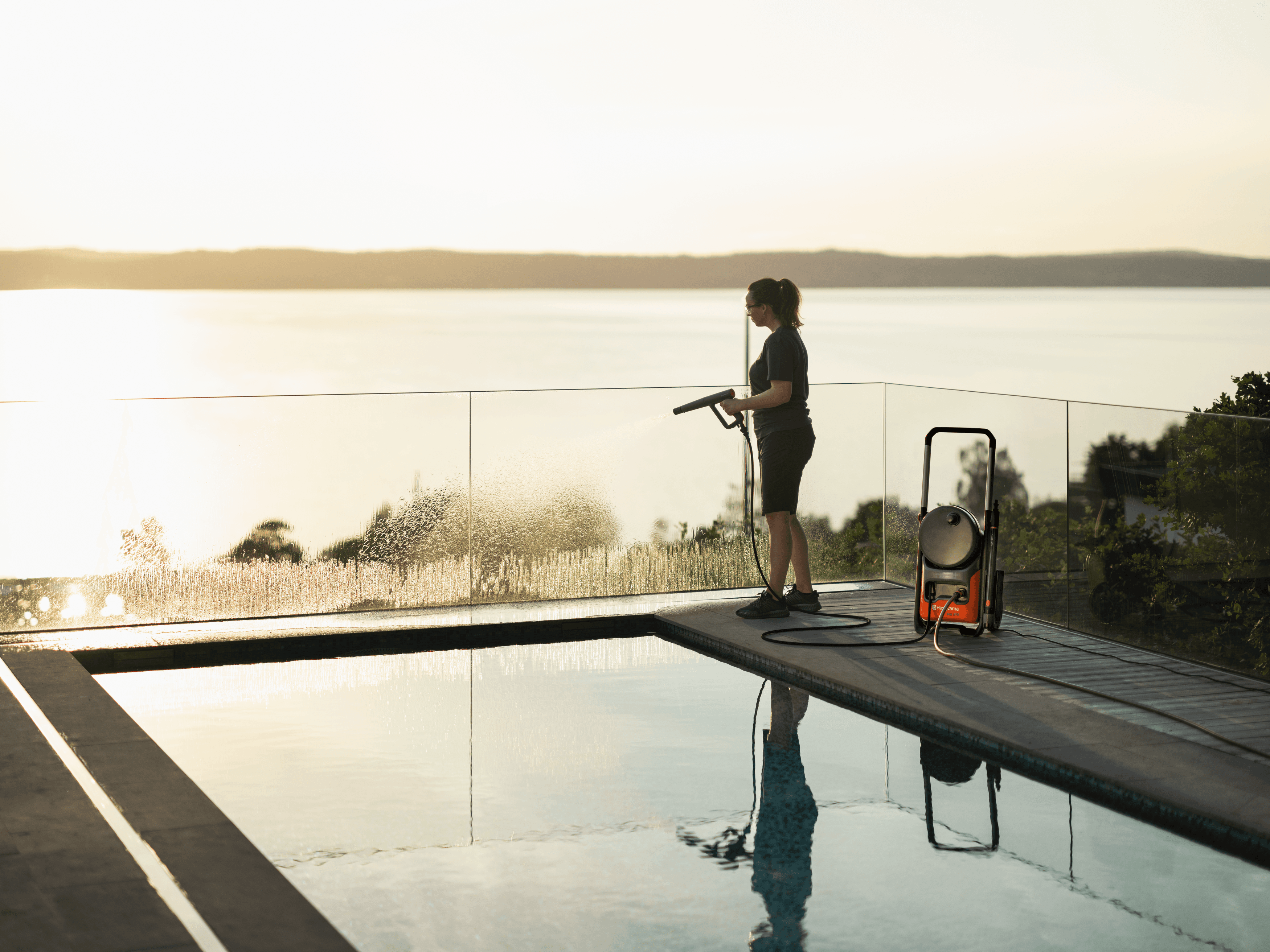 Automower working on downhill in a backyard with a house in the background